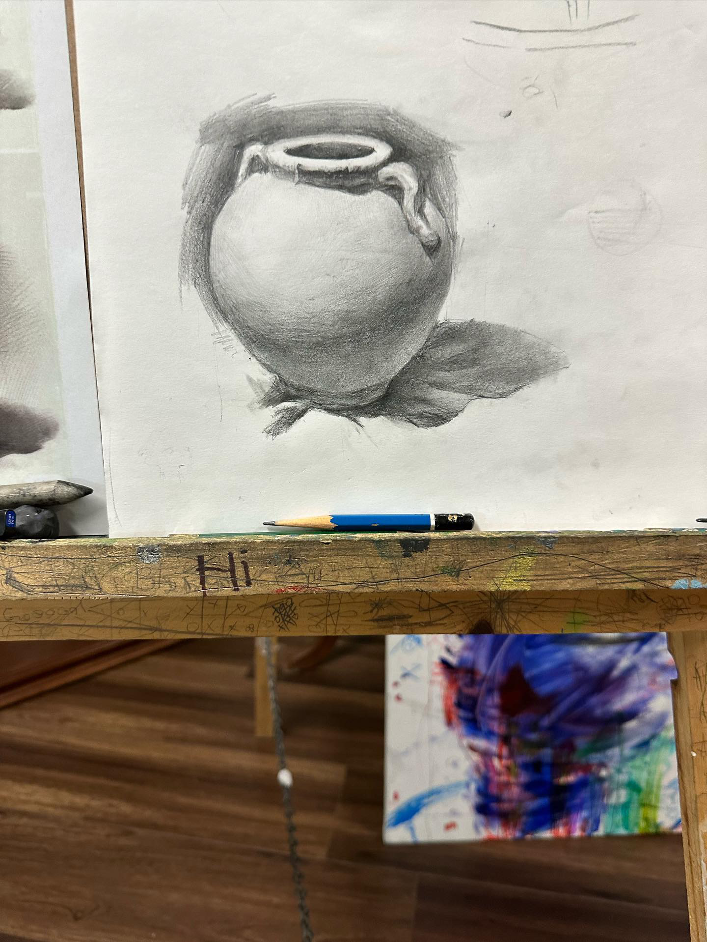 Graphite still life drawing of a round clay pot with a handle on cloth